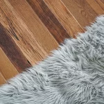 A grey fur rug on a wooden floor