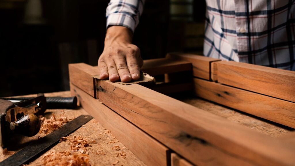 a woodworker distressing wood using a sandpaper