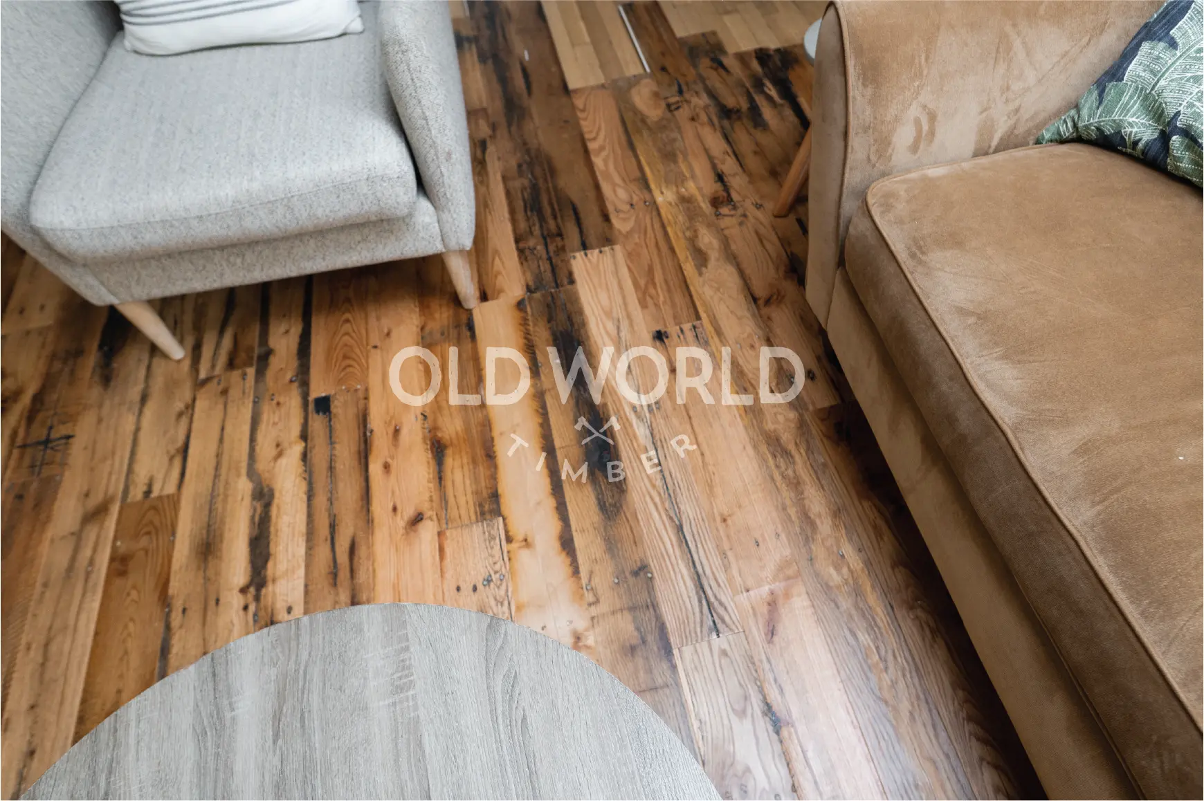 Antique reclaimed oak planks used in a living room setting, showcasing the natural grain, nail holes, and saw marks typical of industrial heritage.