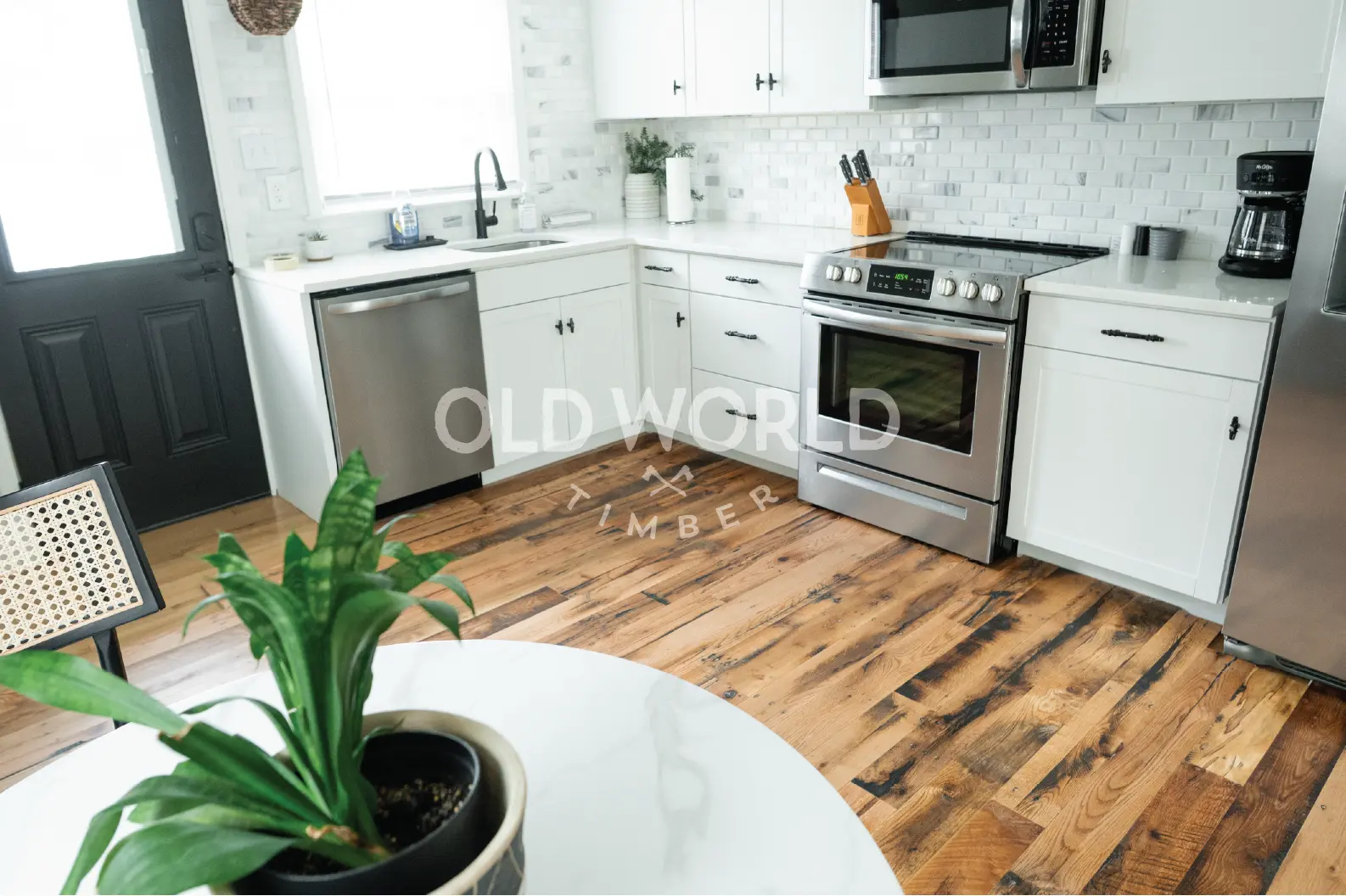 Reclaimed engineered oak floors bringing contrast and history to a kitchen with white cabinetry, subway tile backsplash, and stainless steel appliances.