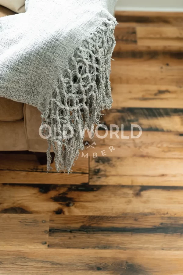 Close-up of Industrial Oak engineered flooring showing rustic character marks and weathered texture beneath a woven gray throw.