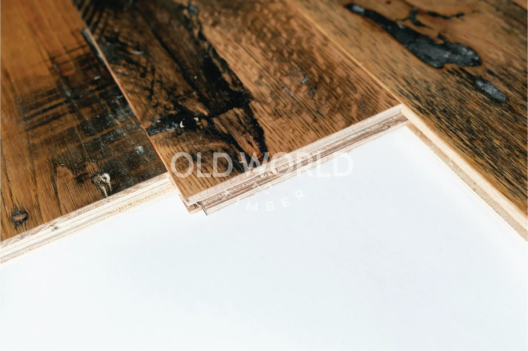 Detailed view of tongue and groove profile of reclaimed engineered oak planks with industrial wear, layered plywood core visible.