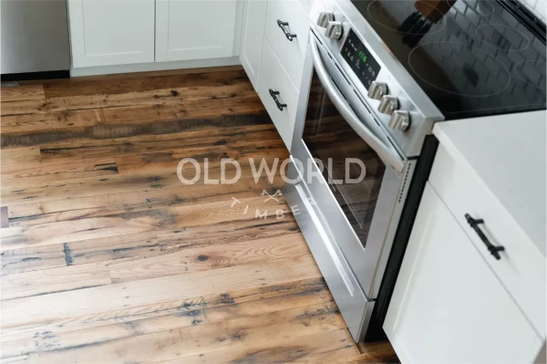 A reclaimed Industrial Oak Engineered floor with vintage charm installed under a stainless steel oven in a white shaker kitchen.