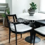 Reclaimed industrial oak engineered flooring installed under a round white dining table and black chair, featuring visible saw blade marks and patina.