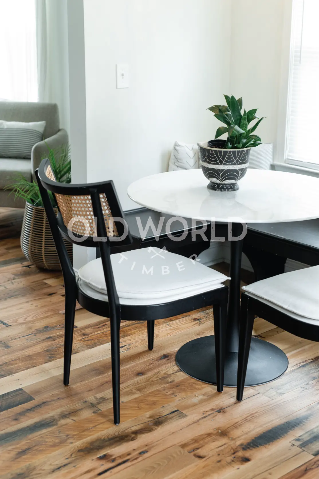 Reclaimed industrial oak engineered flooring installed under a round white dining table and black chair, featuring visible saw blade marks and patina.