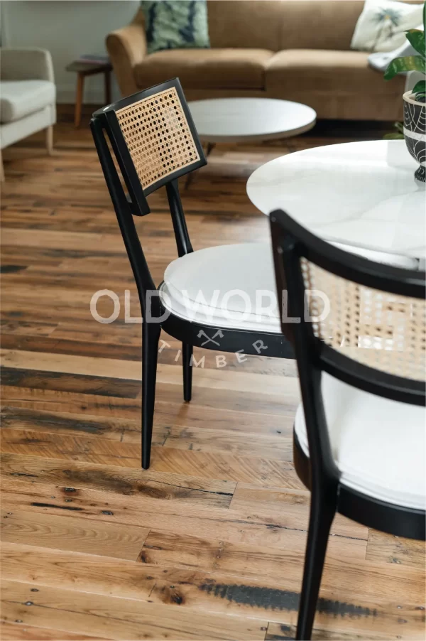 Reclaimed Industrial Oak flooring beneath black dining chairs with cane backs in a bright open-concept kitchen-living space.