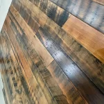 A person standing on a wooden floor in a kitchen.