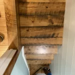A person is standing on a wooden staircase.