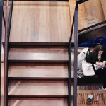 a woman with a laptop sitting under reclaimed custom stair treads for wooden steps