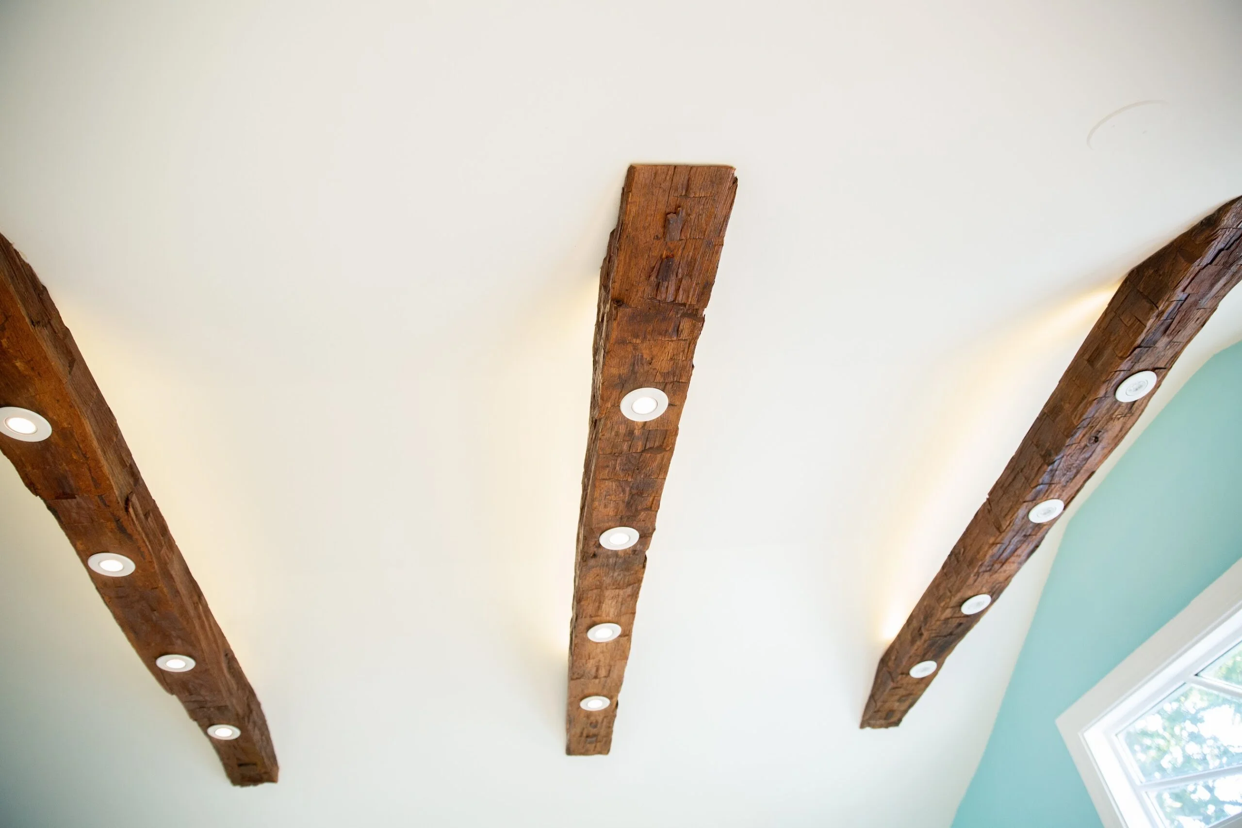 a white ceiling with rustic box beams and white recessed lights