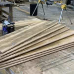 Uninstalled reclaimed stair treads for wooden steps placed on a table in a wood workshop