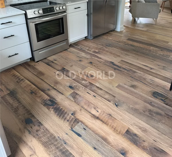 A close-up of Old World Timber’s Heartland Barnwood Mixed Oak engineered reclaimed flooring in a modern white kitchen with stainless steel appliances.