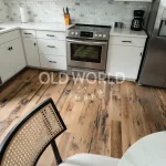 Kitchen corner view of reclaimed Heartland Barnwood Mixed Oak engineered flooring with rustic charm beneath a cane-back dining chair and stainless appliances.