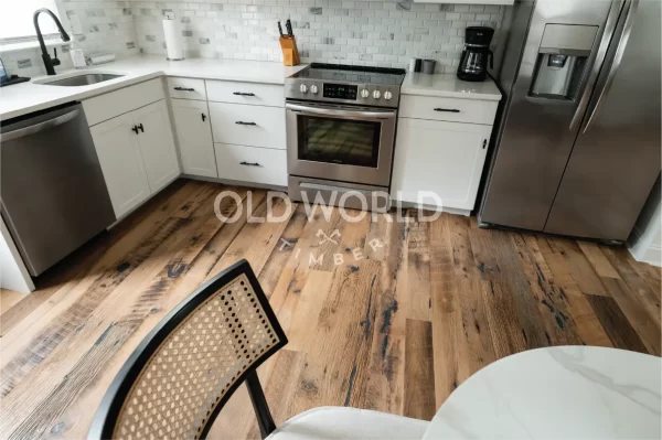 Kitchen corner view of reclaimed Heartland Barnwood Mixed Oak engineered flooring with rustic charm beneath a cane-back dining chair and stainless appliances.