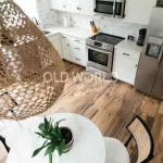 Overhead view of Heartland Barnwood Mixed Oak engineered reclaimed flooring in a white kitchen with marble dining table and woven light fixture.