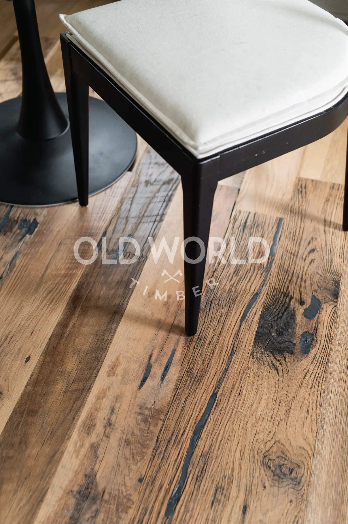 Close-up of Old World Timber’s Heartland Barnwood Mixed Oak engineered reclaimed flooring beneath a dining chair, showing knots and weathered grain.