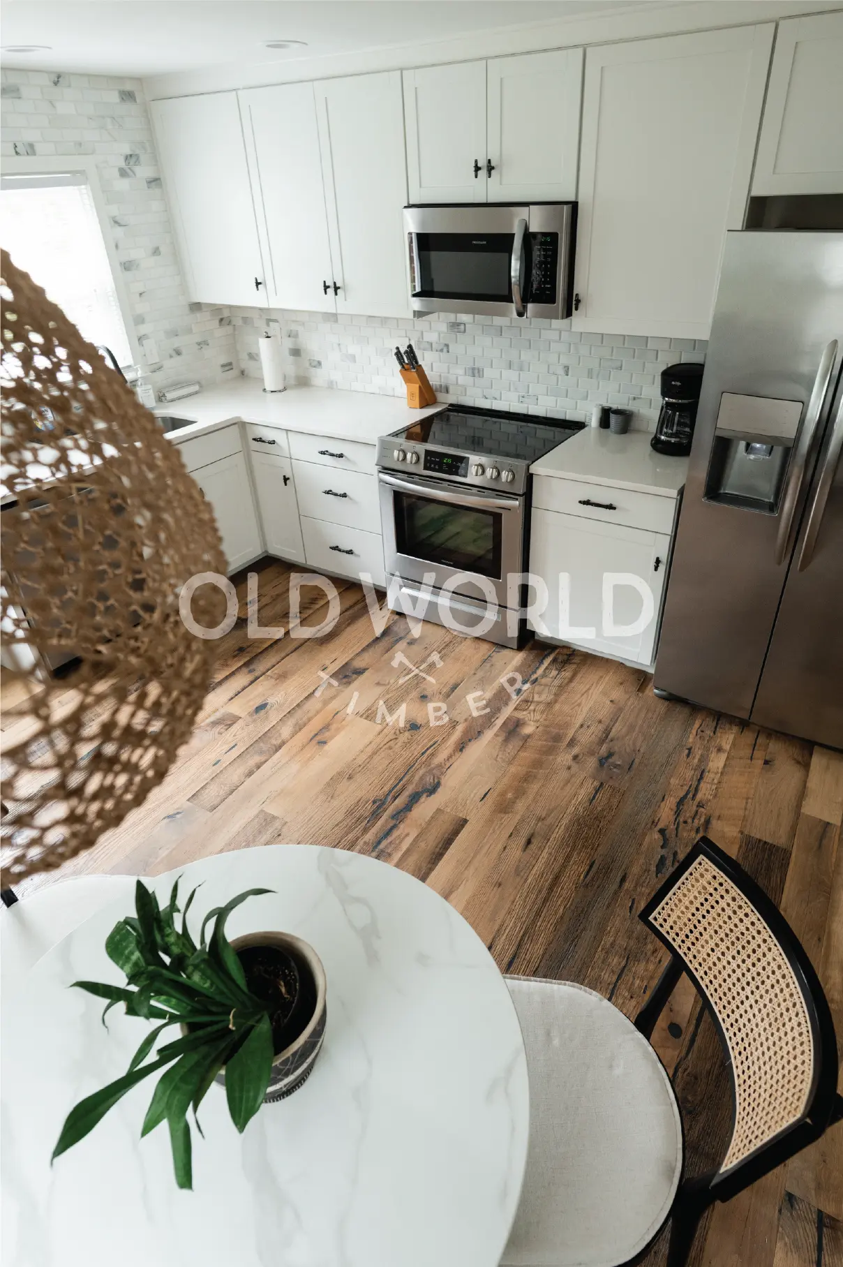 Heartland Barnwood Mixed Oak reclaimed engineered flooring in a naturally lit kitchen with stainless steel appliances and dining table.