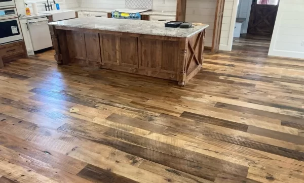 Wide view of Heartland Barnwood Mixed Oak engineered reclaimed flooring in a rustic kitchen with large wood island and granite countertop.