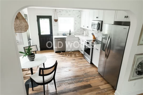 Entry view into a white kitchen featuring Old World Timber’s Heartland Barnwood Mixed Oak engineered reclaimed wood flooring.