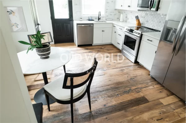 Wide view of Heartland Barnwood Mixed Oak engineered reclaimed flooring in a rustic kitchen with large wood island and granite countertop.
