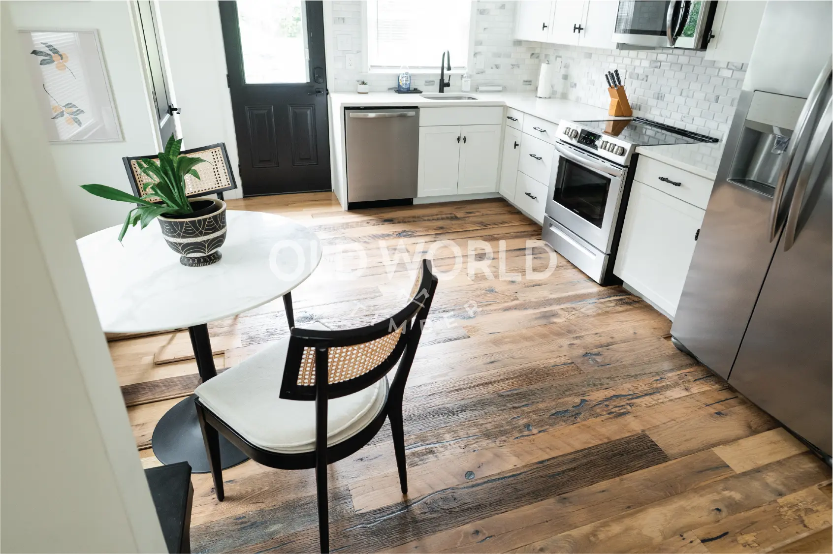 Wide view of Heartland Barnwood Mixed Oak engineered reclaimed flooring in a rustic kitchen with large wood island and granite countertop.