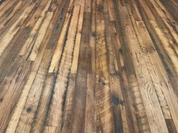 Expansive floor view of Old World Timber’s reclaimed Heartland Barnwood Mixed Oak engineered flooring featuring a variety of tones, saw marks, and rustic patina in a continuous plank layout.