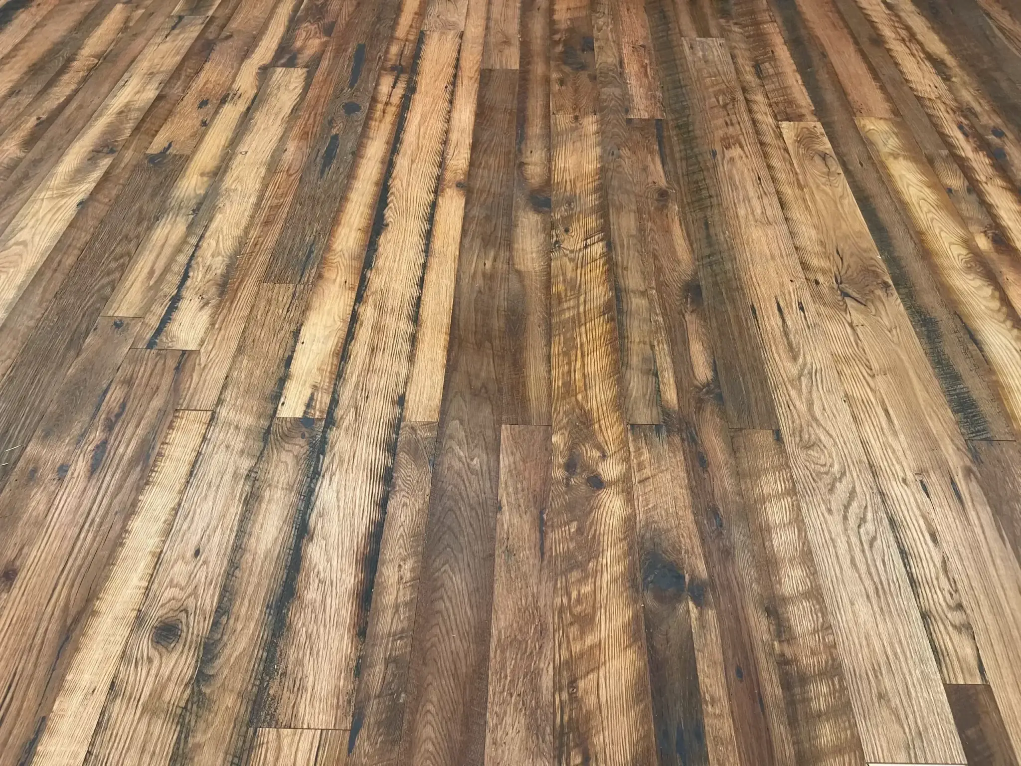Expansive floor view of Old World Timber’s reclaimed Heartland Barnwood Mixed Oak engineered flooring featuring a variety of tones, saw marks, and rustic patina in a continuous plank layout.