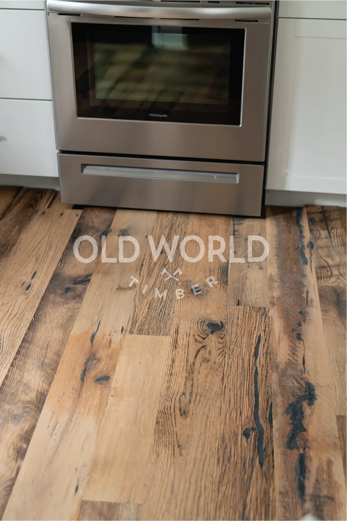 Old World Timber’s engineered Heartland Barnwood flooring beneath a stainless Frigidaire oven, showcasing reclaimed rustic charm.