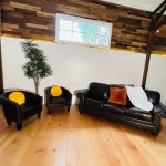 Stylish living space with reclaimed Douglas Fir vertical grain engineered flooring, dark leather seating, and rustic reclaimed wood wall paneling for contrast.