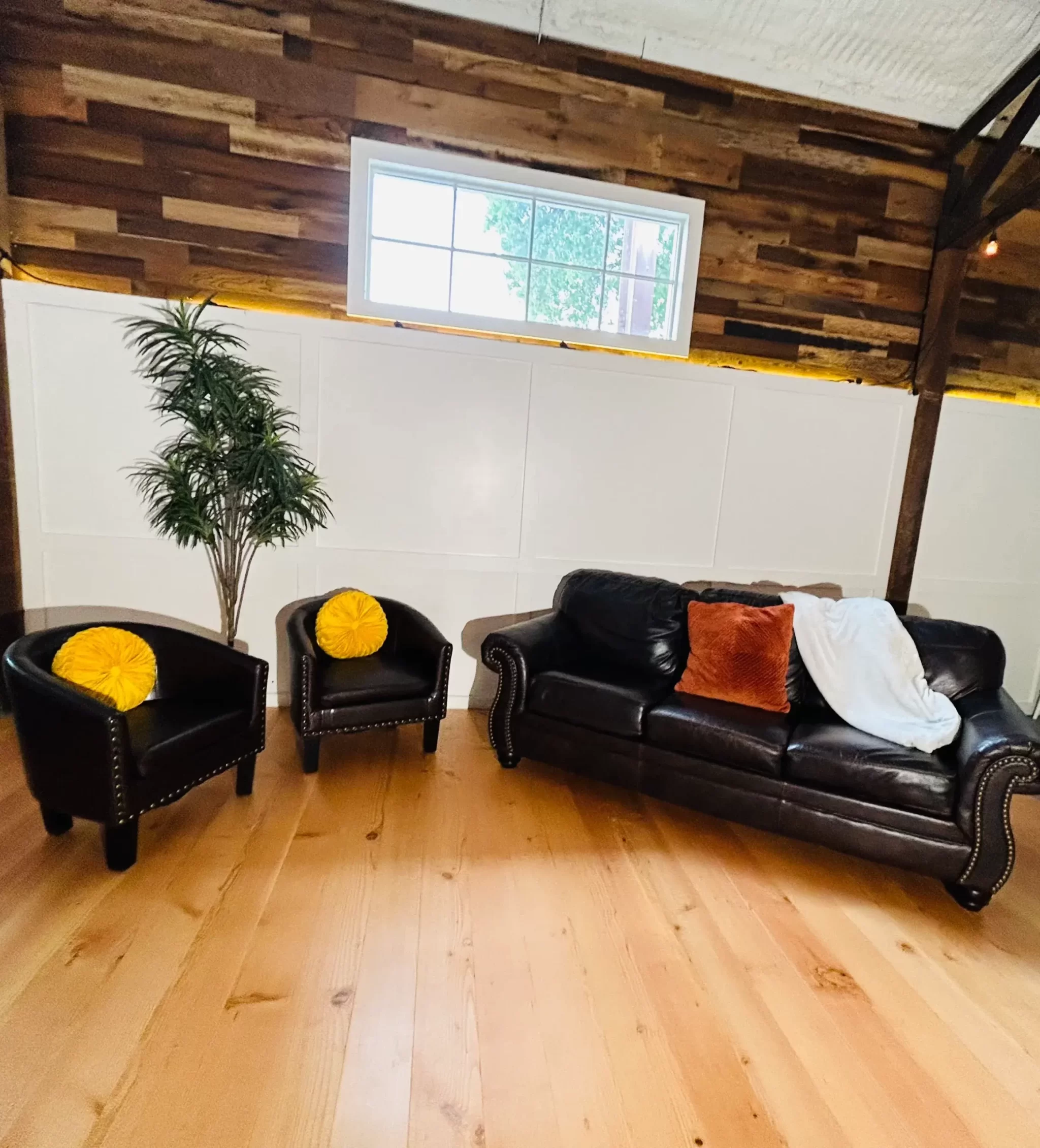 Stylish living space with reclaimed Douglas Fir vertical grain engineered flooring, dark leather seating, and rustic reclaimed wood wall paneling for contrast.