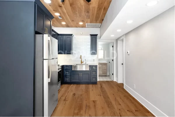 Elegant kitchen with navy cabinets and Modern Harvest engineered oak flooring and ceiling, featuring sustainably sourced planks with natural character.