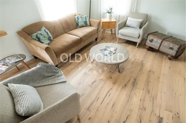 Cozy seating area with soft furnishings and engineered reclaimed oak flooring, showing subtle nail holes and saw kerfs from its industrial past.