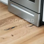 Engineered oak flooring from the Modern Harvest collection extending into a kitchen, highlighting the compatibility of natural textures with stainless steel.