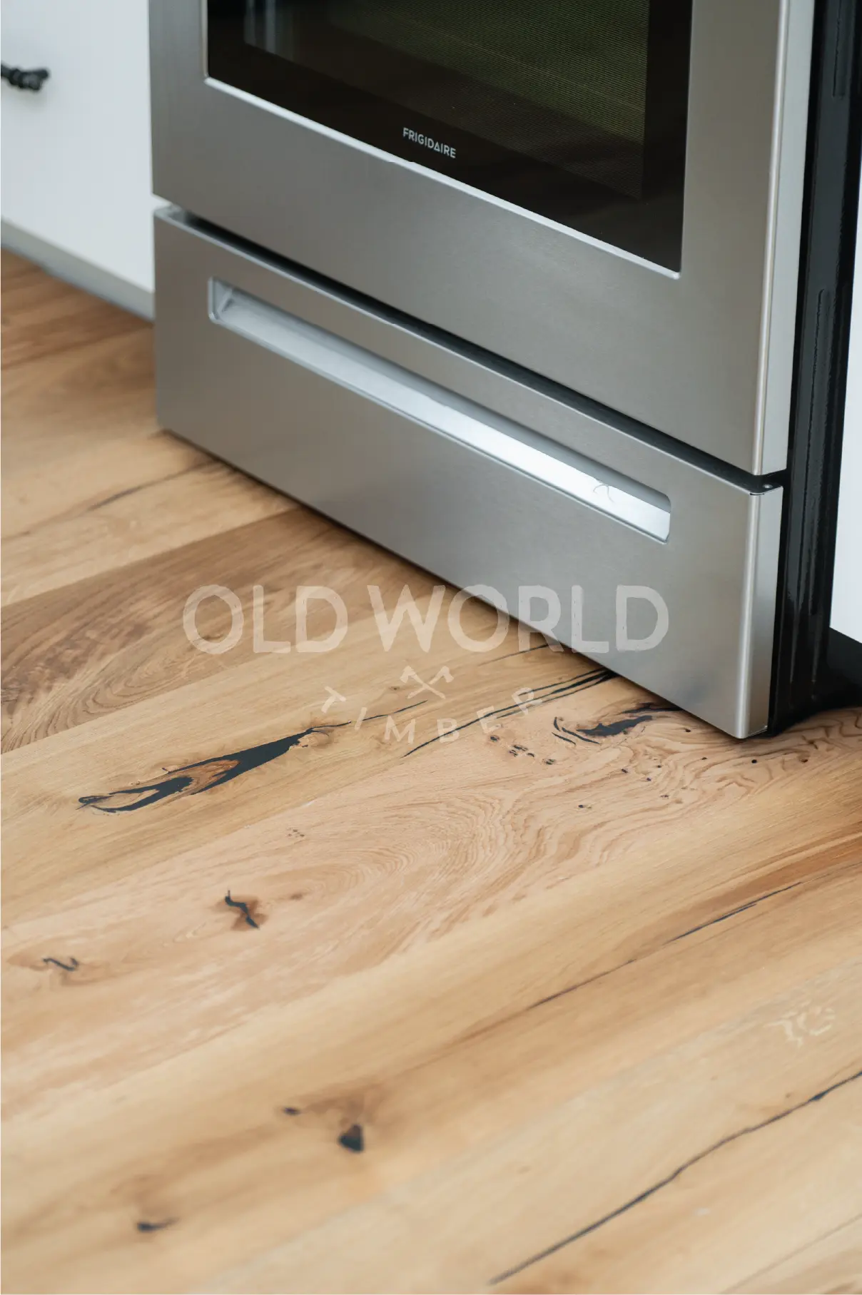 Engineered oak flooring from the Modern Harvest collection extending into a kitchen, highlighting the compatibility of natural textures with stainless steel.