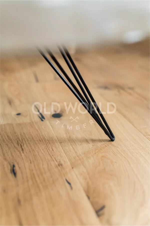 Modern Harvest Oak Flooring shown beneath a black tapered metal table leg, highlighting the reclaimed-style marks and traditional oak texture.