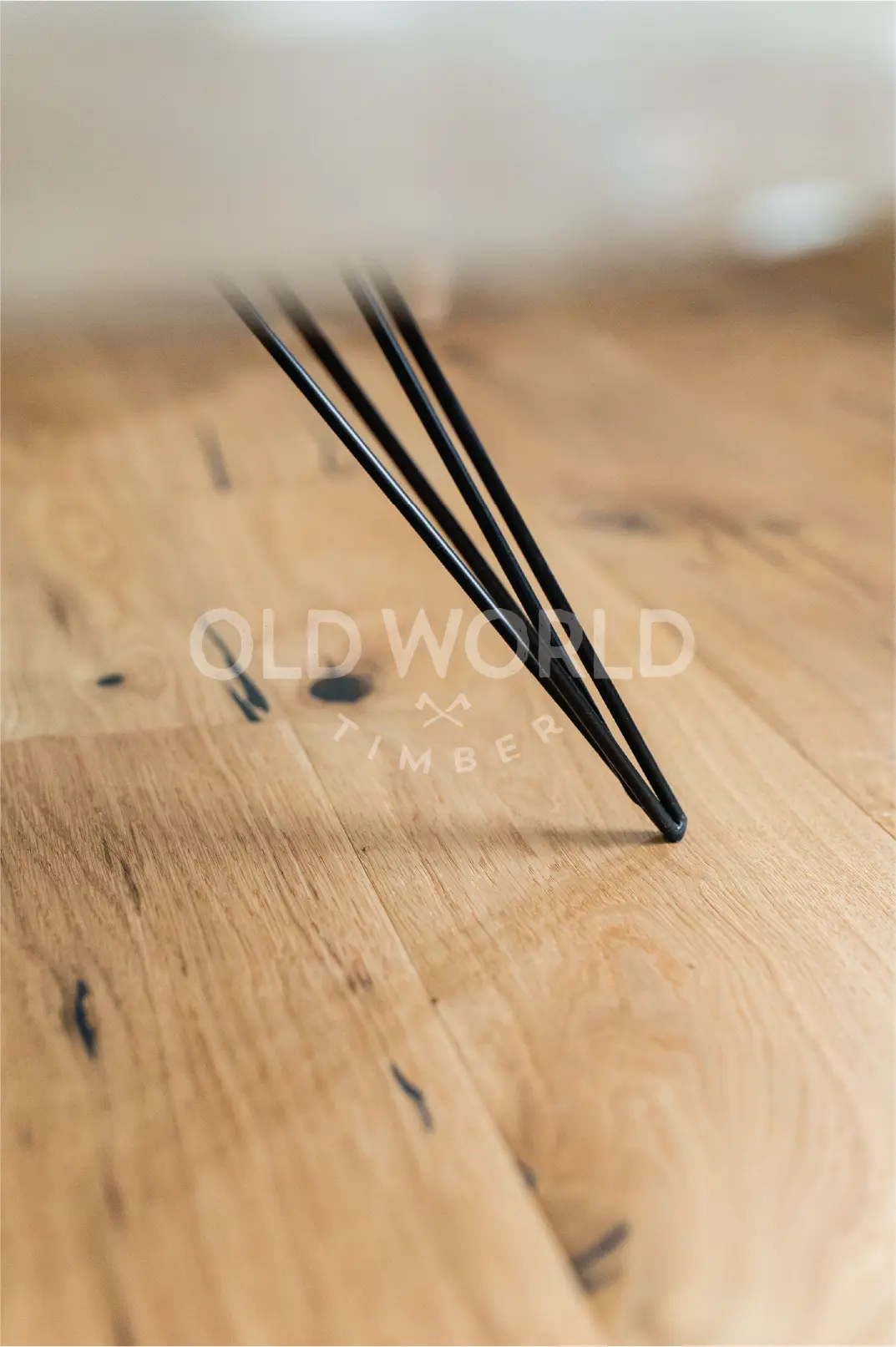 Modern Harvest Oak Flooring shown beneath a black tapered metal table leg, highlighting the reclaimed-style marks and traditional oak texture.