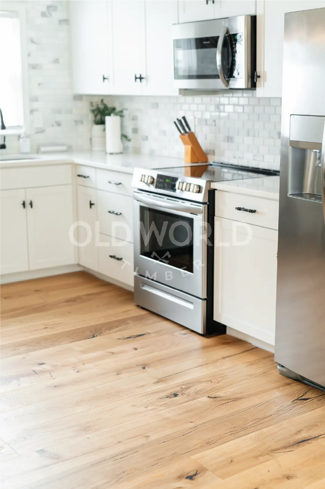 Sustainably sourced Modern Harvest Engineered Oak Flooring in a sunlit kitchen with white cabinetry and stainless steel appliances.