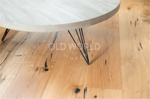 Close-up of black table legs on Modern Harvest engineered oak floor with dark mineral streaks and salvaged-style markings.