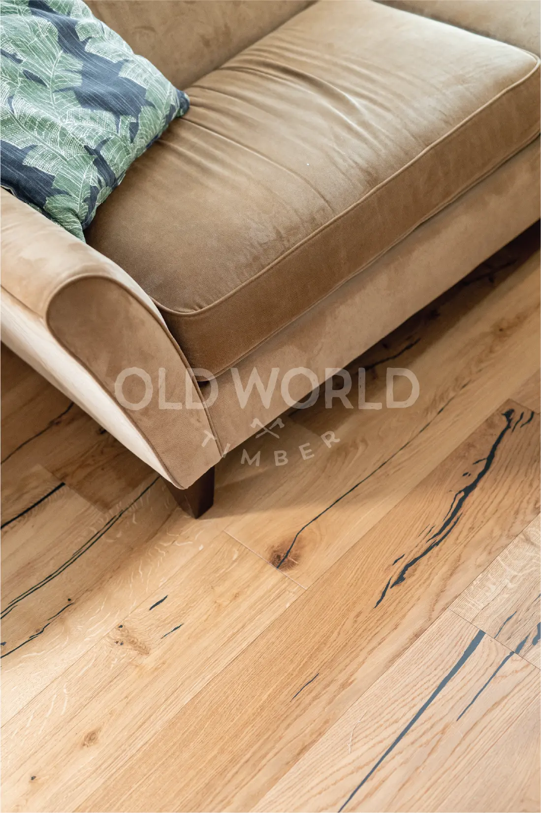 Detail of Modern Harvest oak flooring beneath a beige sofa, showing eco-conscious craftsmanship and salvaged wood inspiration.
