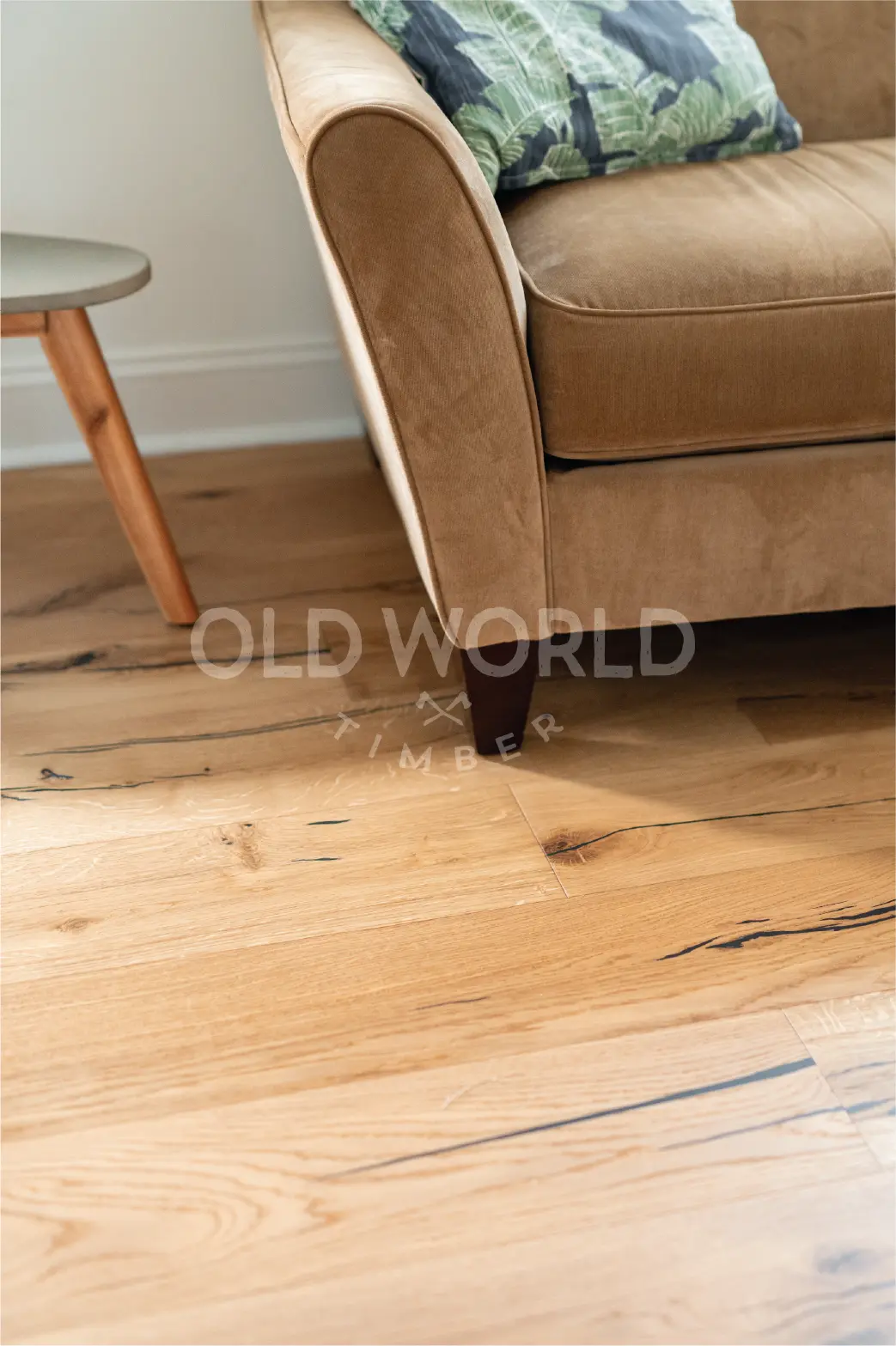 Mid-century couch and side table with Modern Harvest engineered oak flooring underneath, highlighting blackened character marks and soft grain.