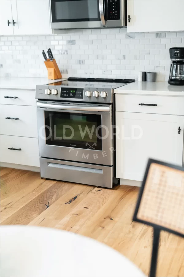 Stainless steel oven and white shaker cabinets set against the natural tones of Modern Harvest engineered oak flooring.