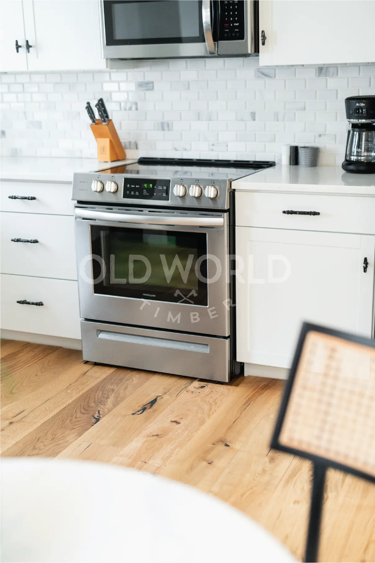 Stainless steel oven and white shaker cabinets set against the natural tones of Modern Harvest engineered oak flooring.