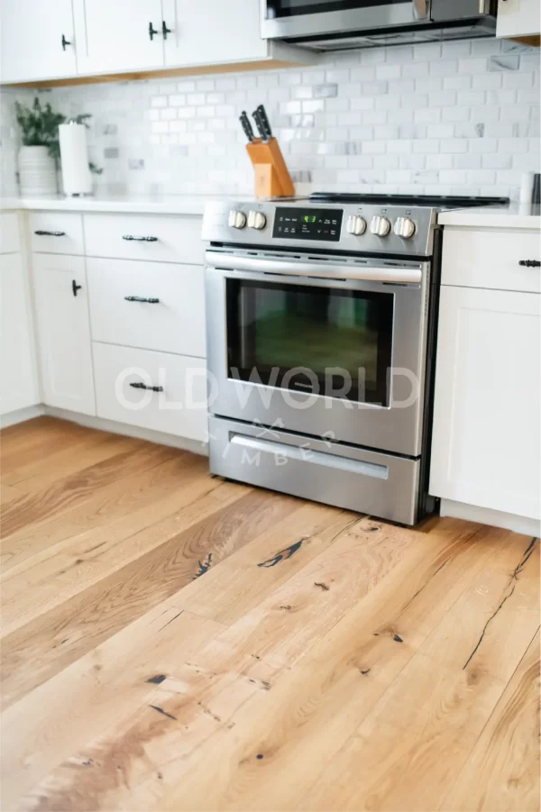 Close-up of Modern Harvest engineered oak flooring beneath a Frigidaire stove with white cabinets and brushed metal hardware.