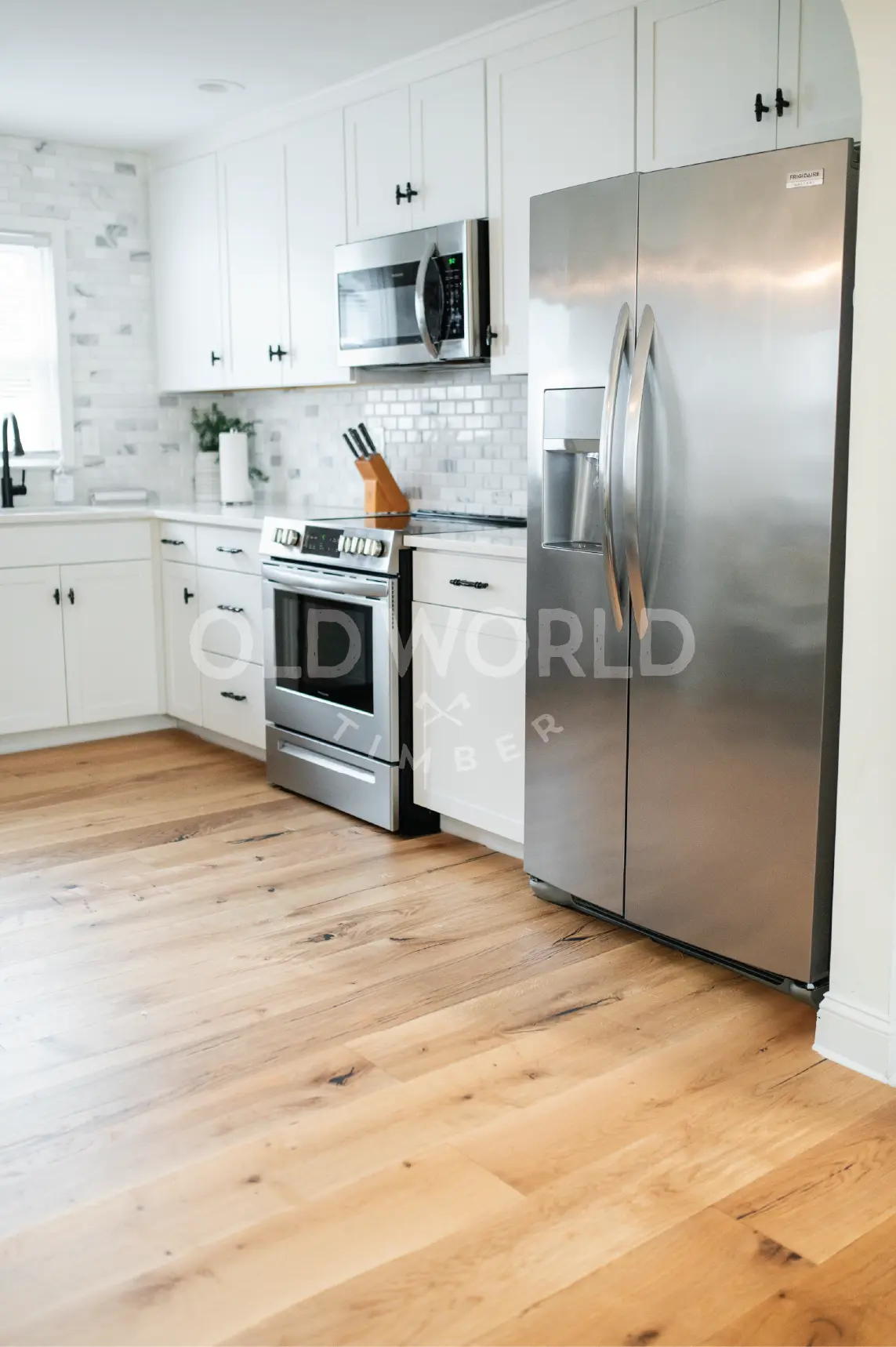 Frontal view of stainless steel appliances and subway tile backsplash atop Modern Harvest engineered flooring with warm oak tones and clean lines.