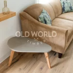 Detailed image of reclaimed white oak flooring beneath a textured gray throw, showing the natural beauty and imperfections of antique hardwood.