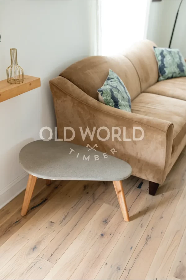 Detailed image of reclaimed white oak flooring beneath a textured gray throw, showing the natural beauty and imperfections of antique hardwood.