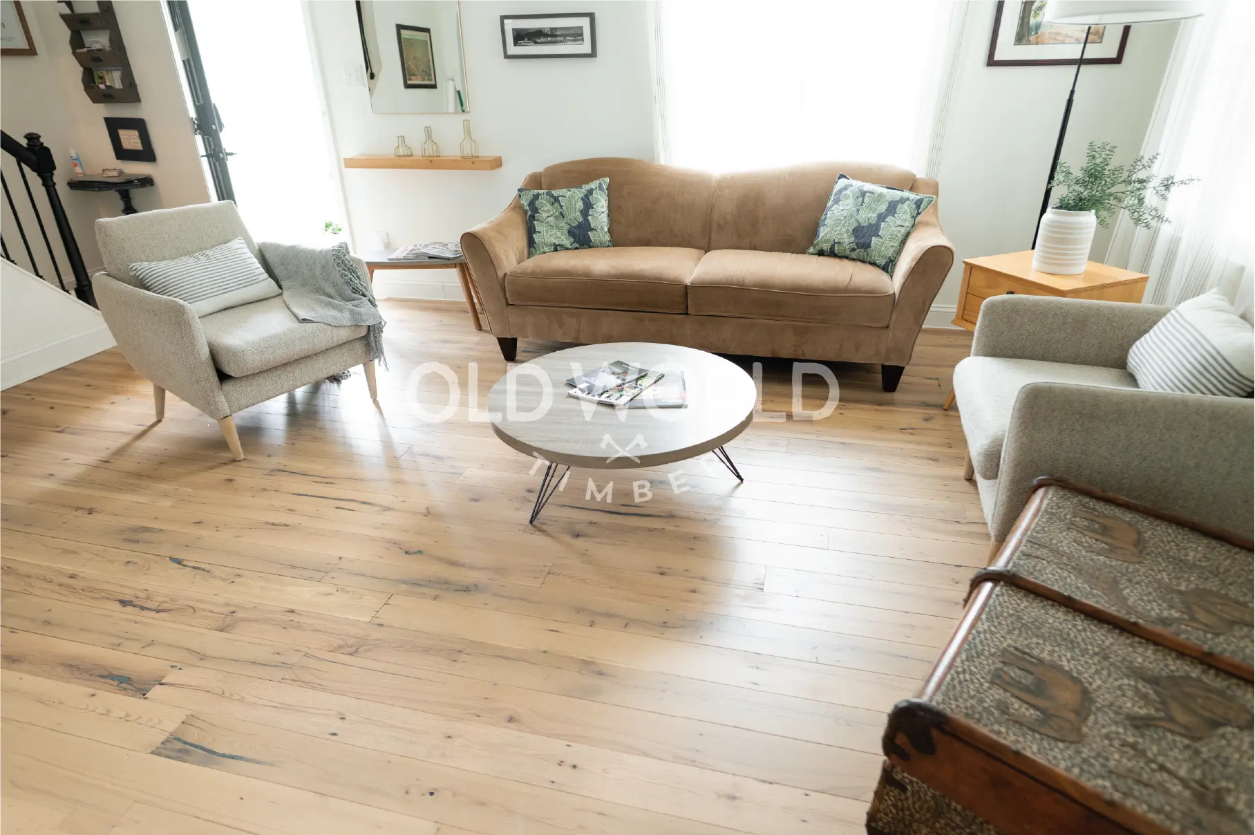 Close-up of reclaimed industrial oak engineered floors with visible saw marks and dark knots beneath a brown couch and modern end table.