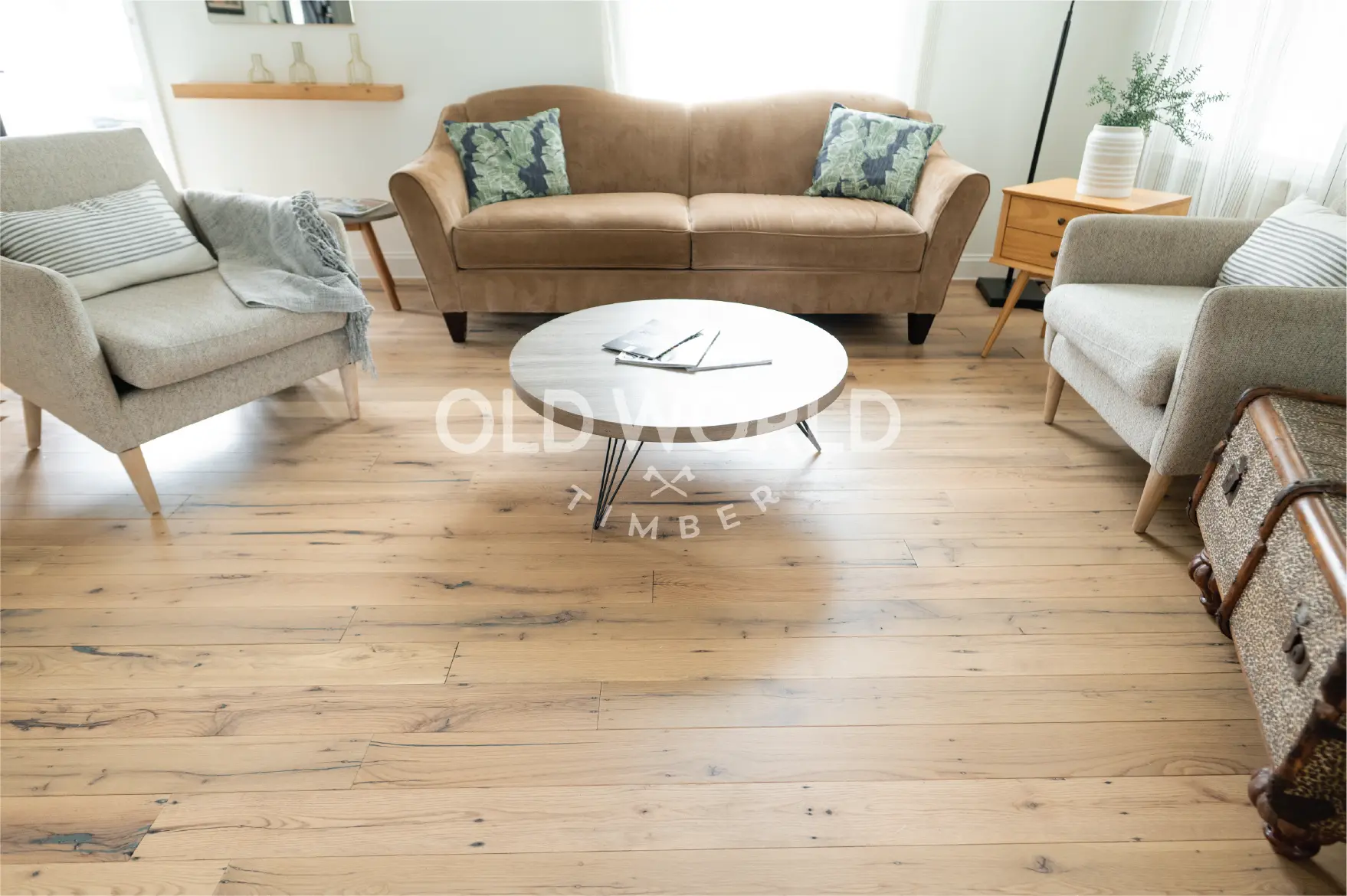 Cozy living room featuring reclaimed white oak engineered flooring with character knots, styled with mid-century modern armchairs and a round coffee table