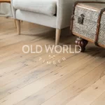 Neutral-toned sofa and modern lamp stand atop clean face reclaimed oak planks with heritage-rich surface marks.