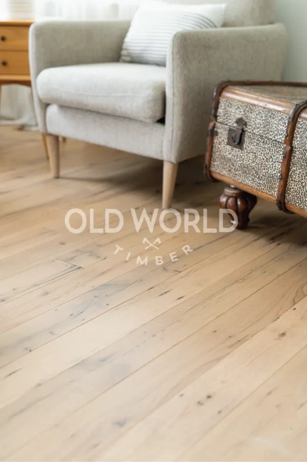 Neutral-toned sofa and modern lamp stand atop clean face reclaimed oak planks with heritage-rich surface marks.